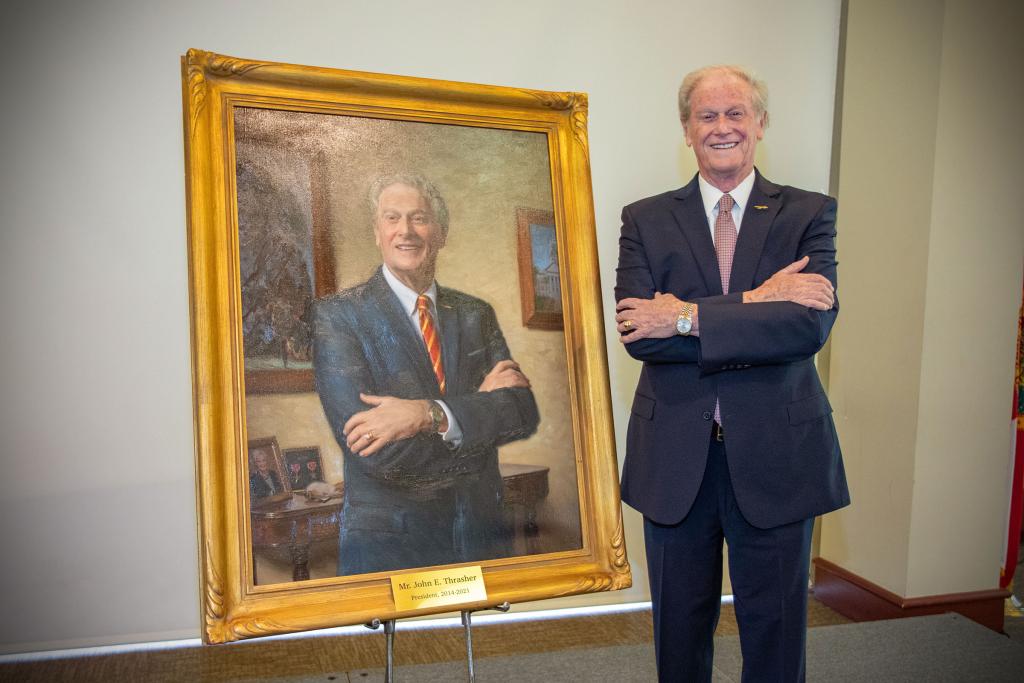 President Emeritus John Thrasher poses with his portrait during the unveiling ceremony April 25, 2022.